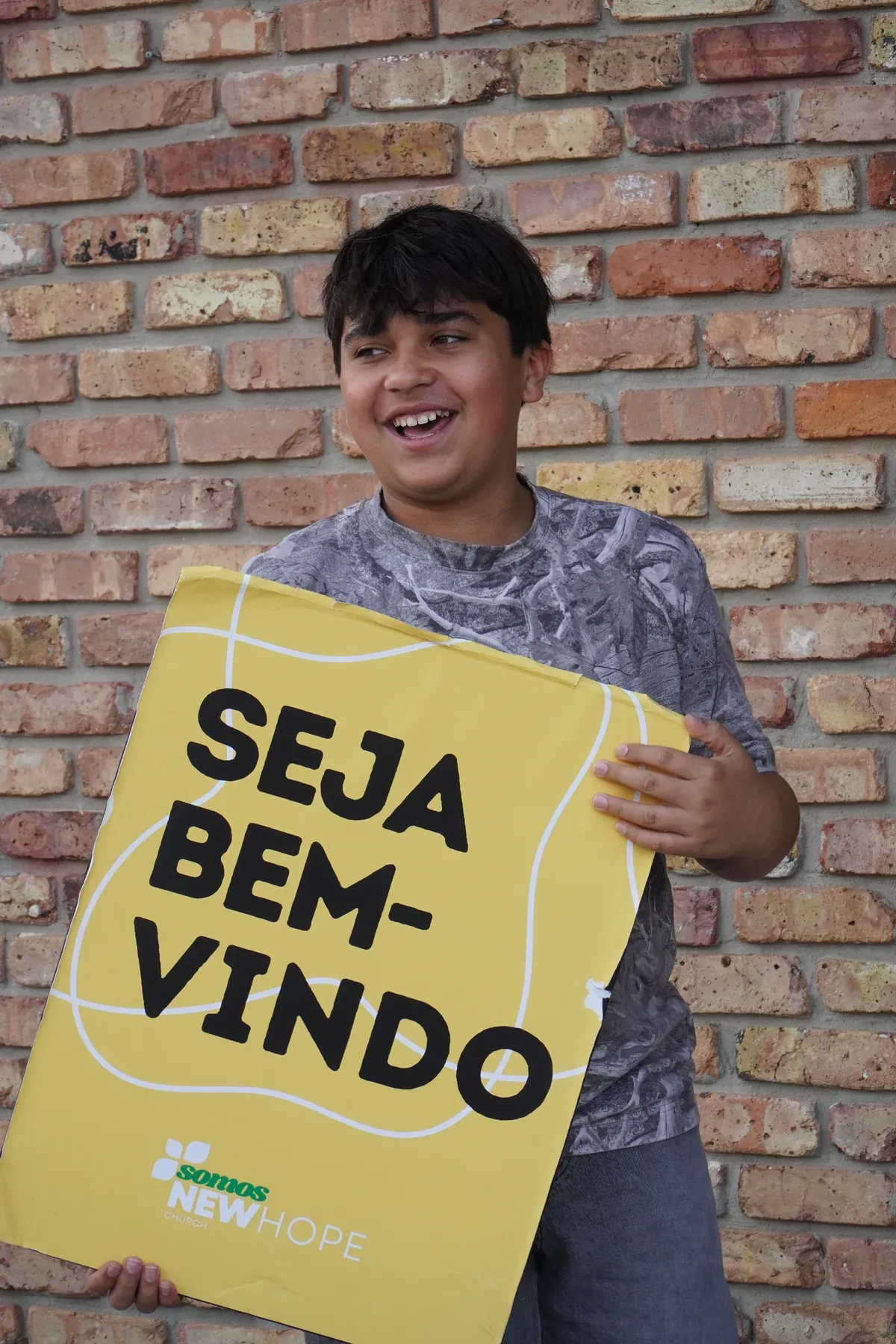 Adolescente da New Hope Church segurando a placa de boas-vindas na entrada